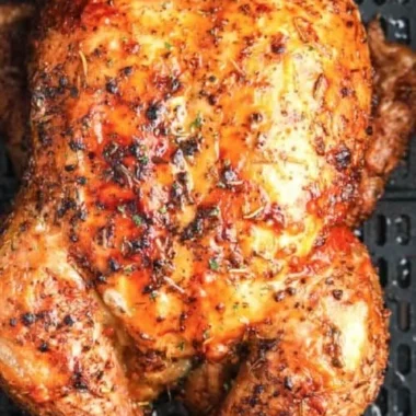 Crispy air fryer whole roasted chicken garnished with herbs on a serving platter