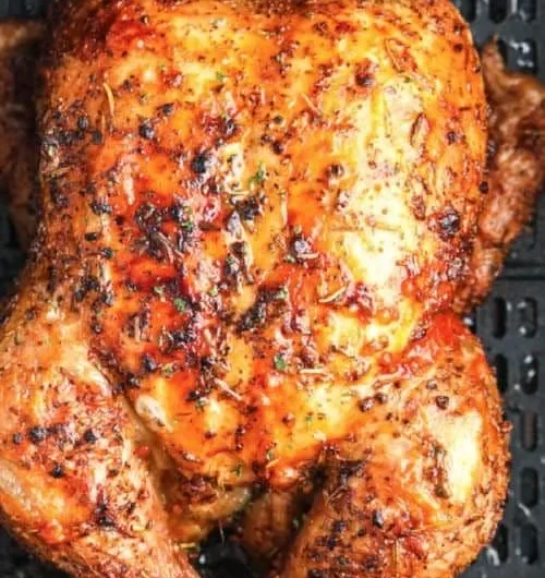 Crispy air fryer whole roasted chicken garnished with herbs on a serving platter