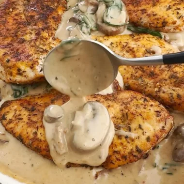 Creamy mushroom chicken dish served on a plate with herbs and spices.