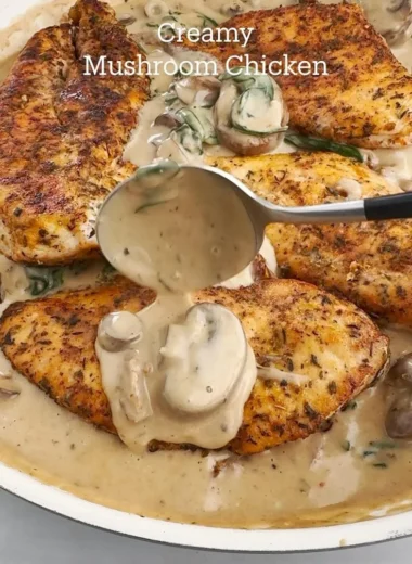 Creamy mushroom chicken dish served on a plate with herbs and spices.