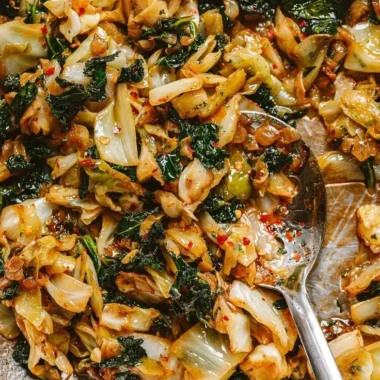 A skillet of garlic sautéed cabbage and kale, garnished with herbs.