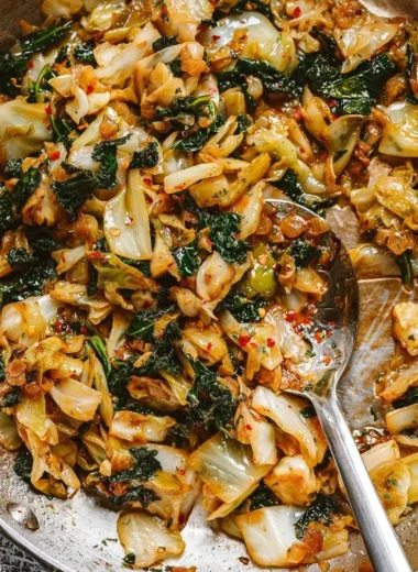 A skillet of garlic sautéed cabbage and kale, garnished with herbs.