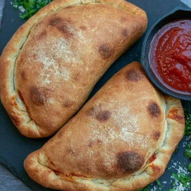 Homemade air fryer calzones filled with cheese and pepperoni on a wooden table.