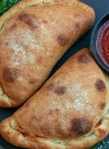 Homemade air fryer calzones filled with cheese and pepperoni on a wooden table.