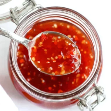 Bottle of homemade sweet chili sauce with peppers and garlic