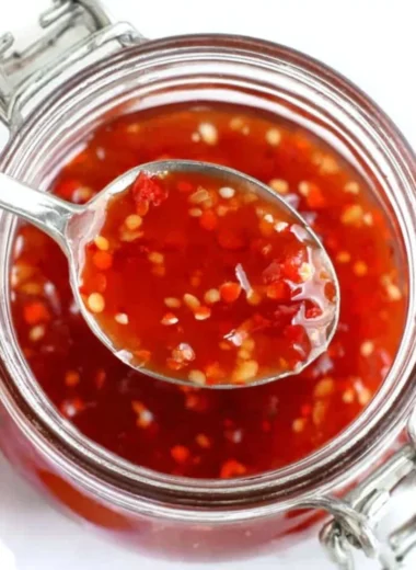 Bottle of homemade sweet chili sauce with peppers and garlic