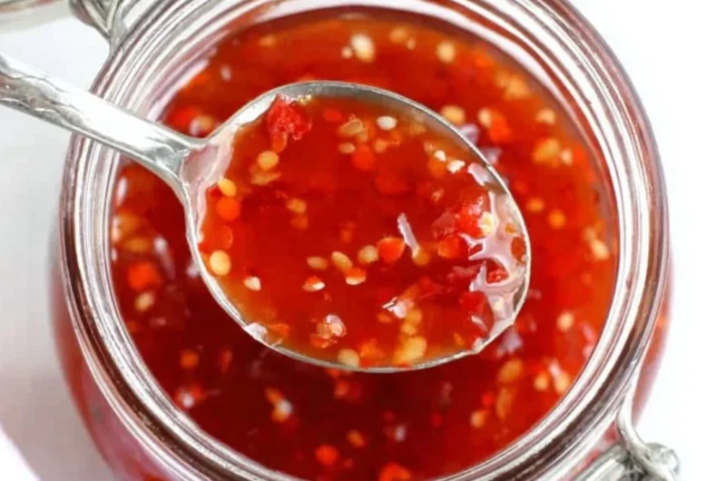 Bottle of homemade sweet chili sauce with peppers and garlic