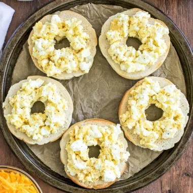 Breakfast pizza bagels topped with eggs, cheese, and vegetables.