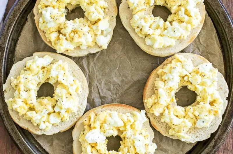 Breakfast pizza bagels topped with eggs, cheese, and vegetables.