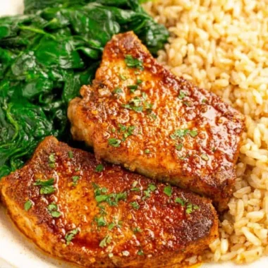 Juicy oven baked pork chops served with rice on a plate.