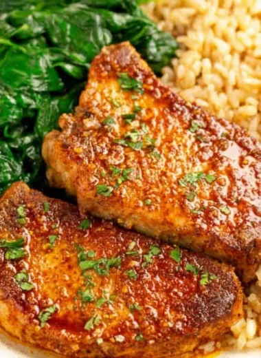 Juicy oven baked pork chops served with rice on a plate.