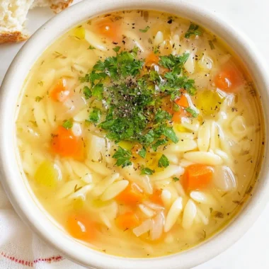 Bowl of hearty orzo soup with vegetables and herbs.