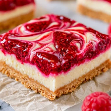 Homemade Raspberry Cheesecake Bars topped with fresh raspberries and a graham cracker crust.