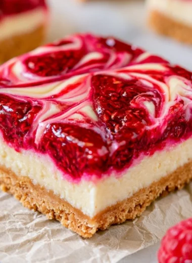 Homemade Raspberry Cheesecake Bars topped with fresh raspberries and a graham cracker crust.