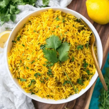 Bowl of delicious turmeric rice garnished with herbs and spices