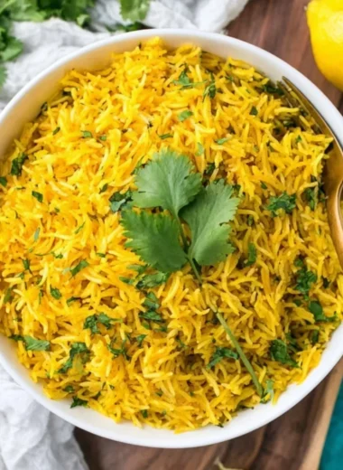 Bowl of delicious turmeric rice garnished with herbs and spices