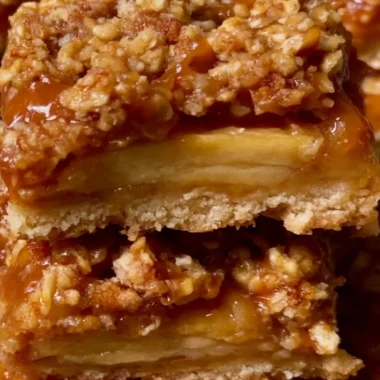 Cozy apple pie bars with a golden crust and apple filling, served on a wooden table.