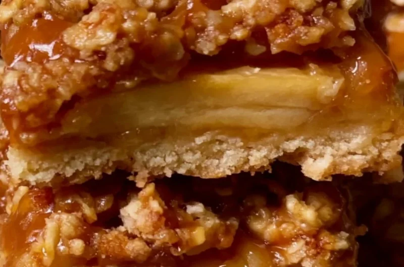 Cozy apple pie bars with a golden crust and apple filling, served on a wooden table.