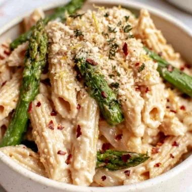 Creamy dairy-free lemon white bean pasta garnished with herbs and lemon zest.
