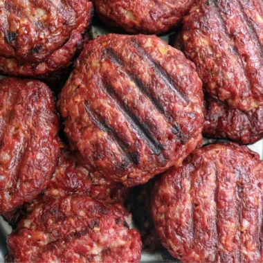 Delicious homemade smoked burgers on a grill, showcasing juicy patties and toppings.