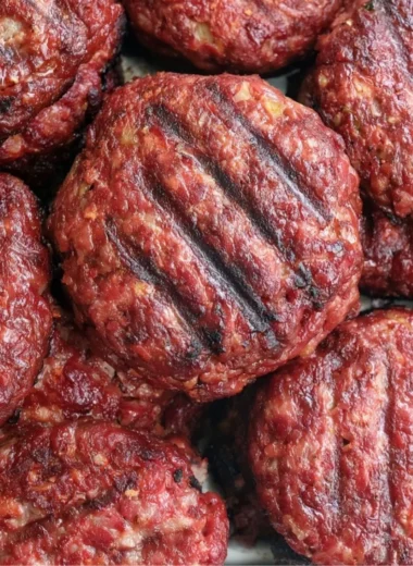 Delicious homemade smoked burgers on a grill, showcasing juicy patties and toppings.