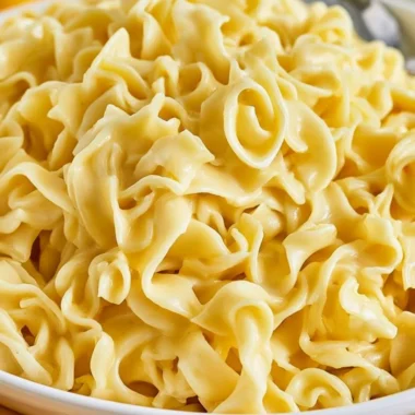 Bowl of cozy creamy cafeteria noodles topped with herbs and spices
